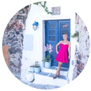Blonde girl in pink dress in front of Santorini blue door