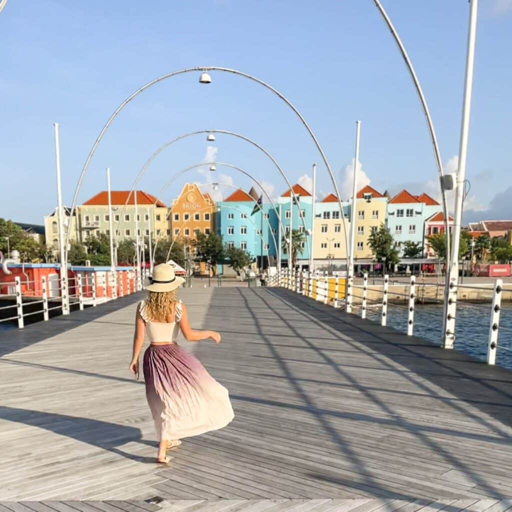 Blonde girl on Queen Emma bridge in front of colorful houses, Willemstad Curacao