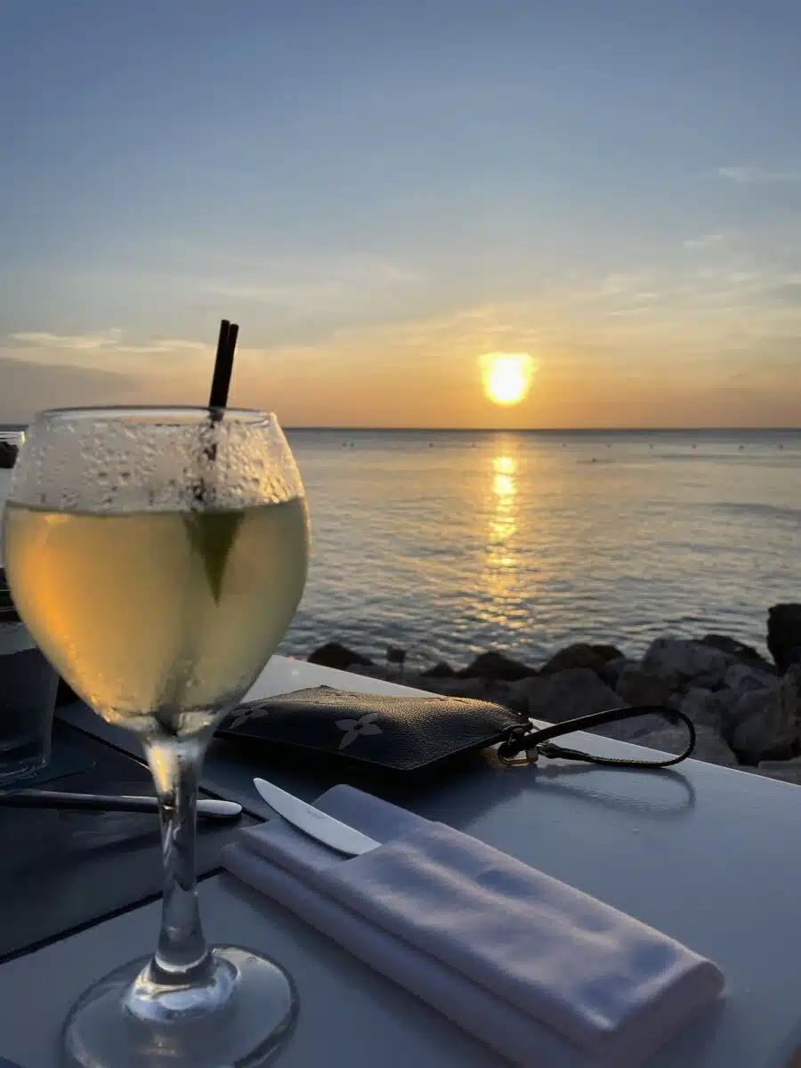 cocktail with sun setting over ocean in the background