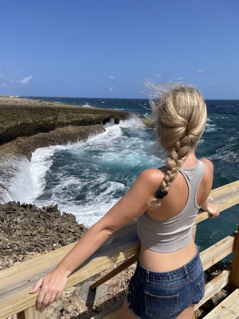 Blonde girl in Shete Boka National Park Curacao in front of waves