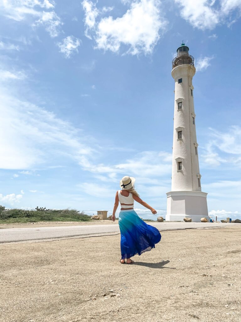 California Lighthouse in Aruba with blonde girl in flowing skirt most instagrammable spots Aruba