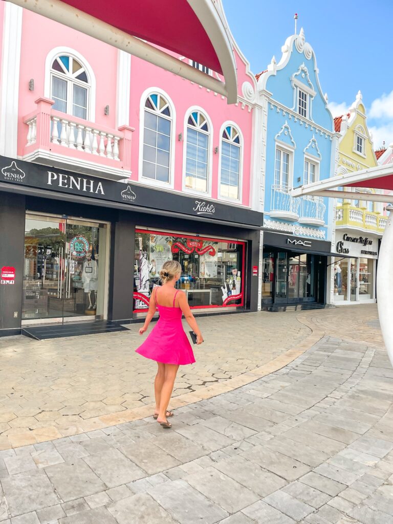 Colorful houses in Aruba Oranjestad with blonde girl in pink dress, Aruba instagram spot
