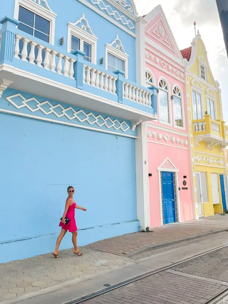 Colorful houses in Aruba Oranjestad with blonde girl in pink dress, Aruba instagram spot