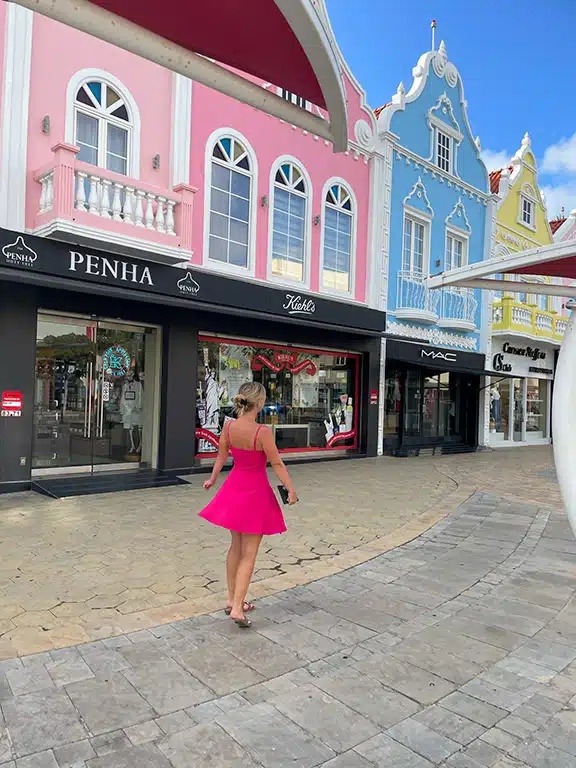 Excited girl walking the shopping streets with beautiful coloured houses in Oranjestad