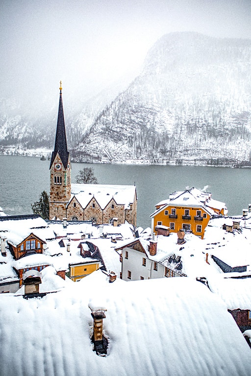 Hallstatt with typical Austrian houses and church covered in snow