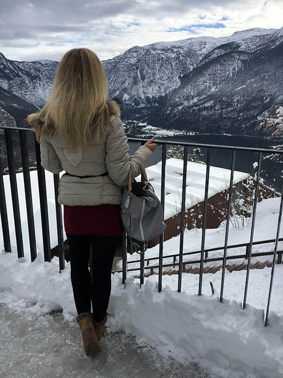 Author posing next to the beautiful view of snowy Hallstatt