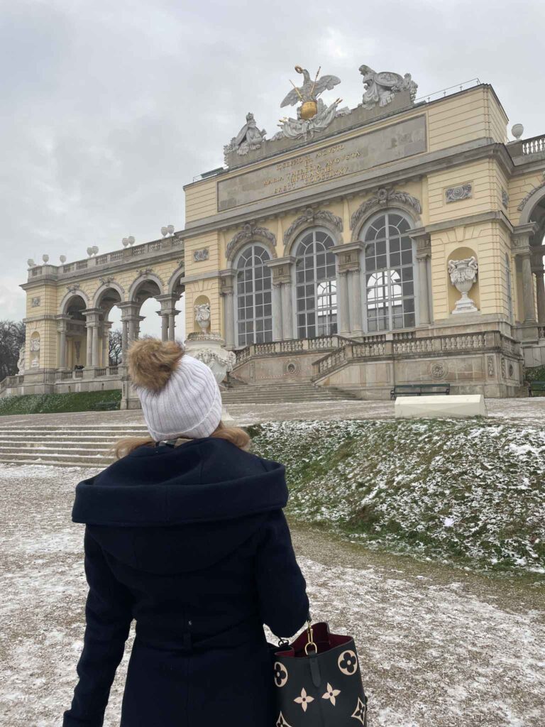 Blonde girl in front of Gloriette building in vienna in winter with snow on the ground