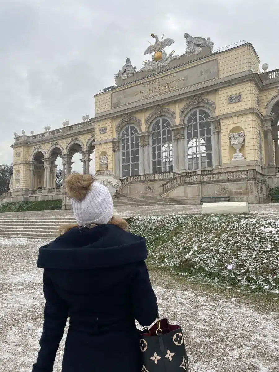 the author in schoenbrunn palace in vienna in winter in a coat and with a hat with some snow on the ground