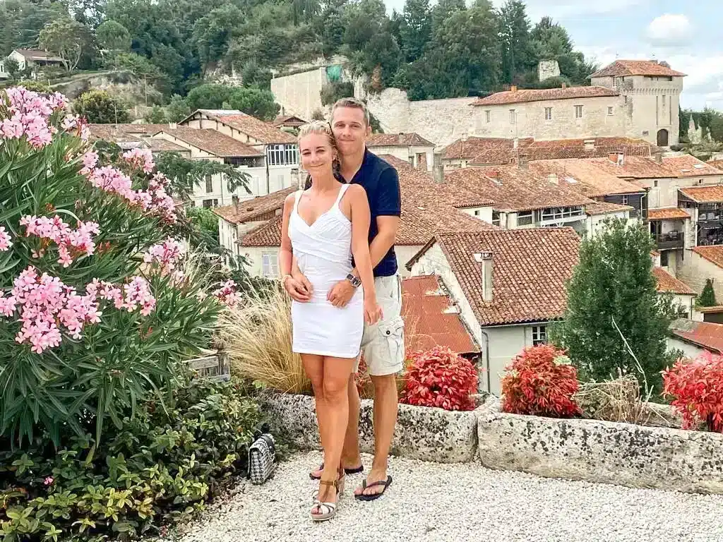 Couple standing on top of a viewpoint in aubeterre overlooking a stunning backdrop of houses