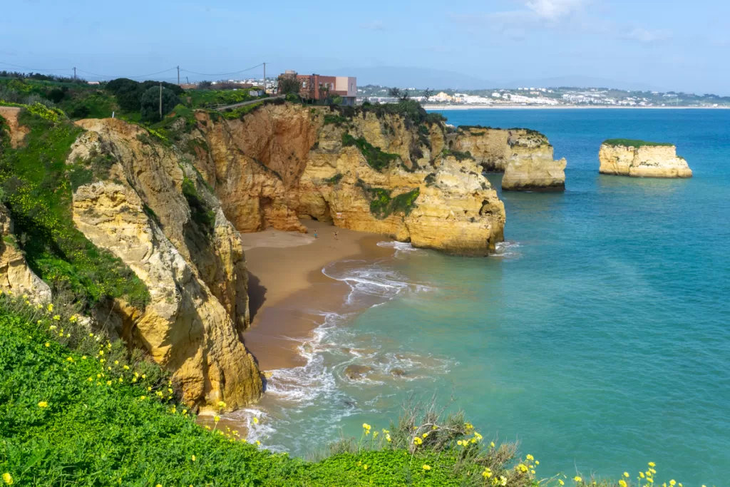 Picture of the algave coast in Portugal from above of a beach with blue water and big cliffs 