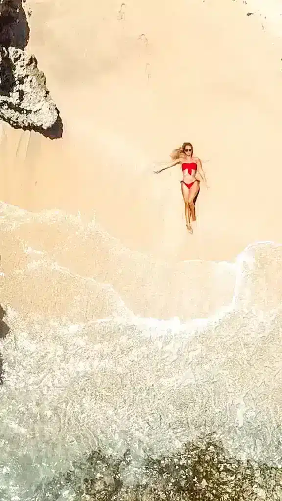 Drone shot of the author lying in the sand and waves coming in in Curacao
