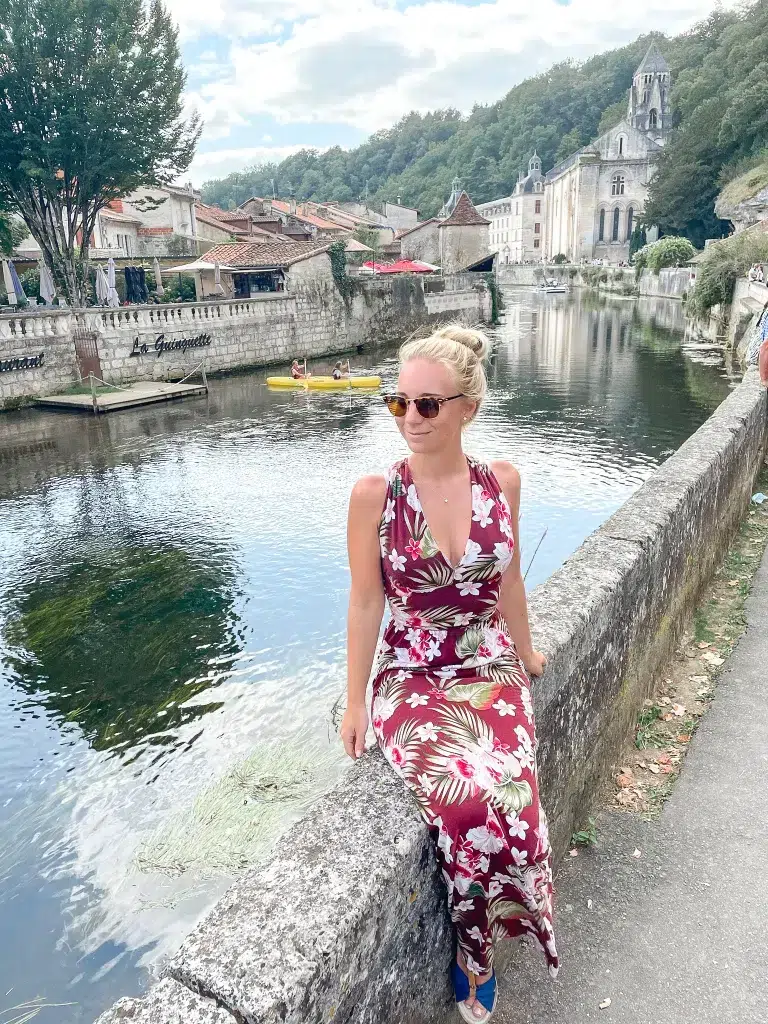 Girl sitting in brantome next to the river overlooking a beautiful castle