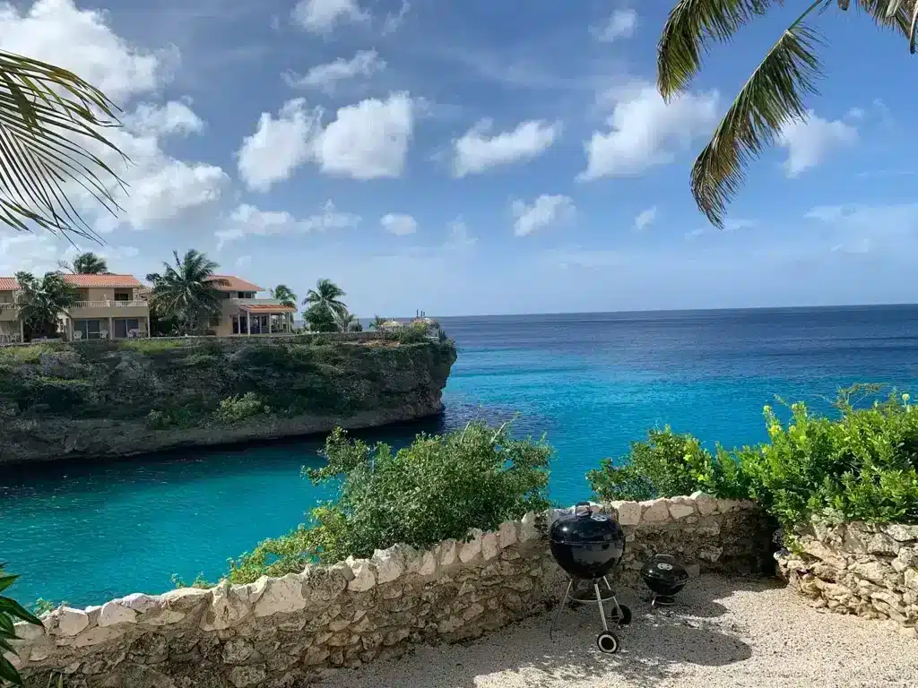 small bay with beautiful clear blue water and a barbeque and palm trees in playa lagun curacao