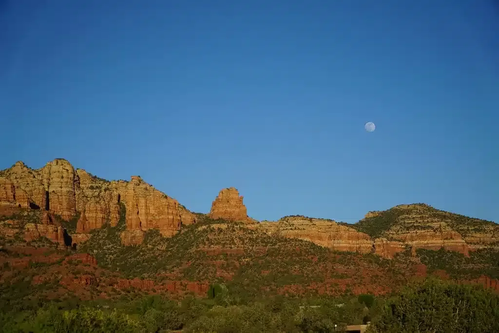Red mountain range in Sedona, Arizona in the evening with moon on the sky