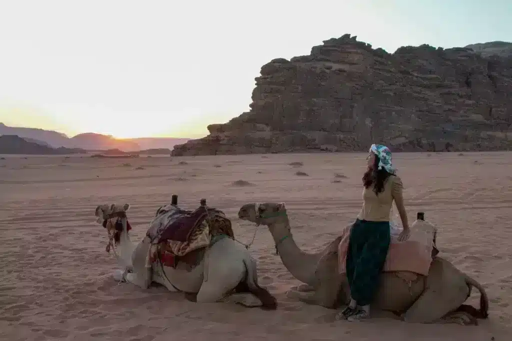 girl with two camels in desert overlooking sunset bucket list adventure experience 