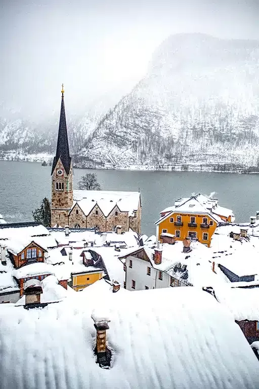 The church of Hallstatt with the village in front and snow covered roofs, the lake is in the background