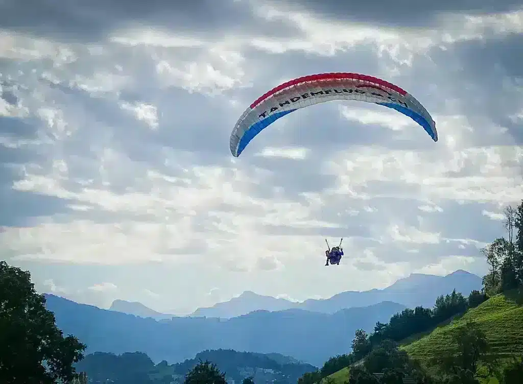 Two people in a paraglider flying over mount pilatus in switzerland adventure bucket list item