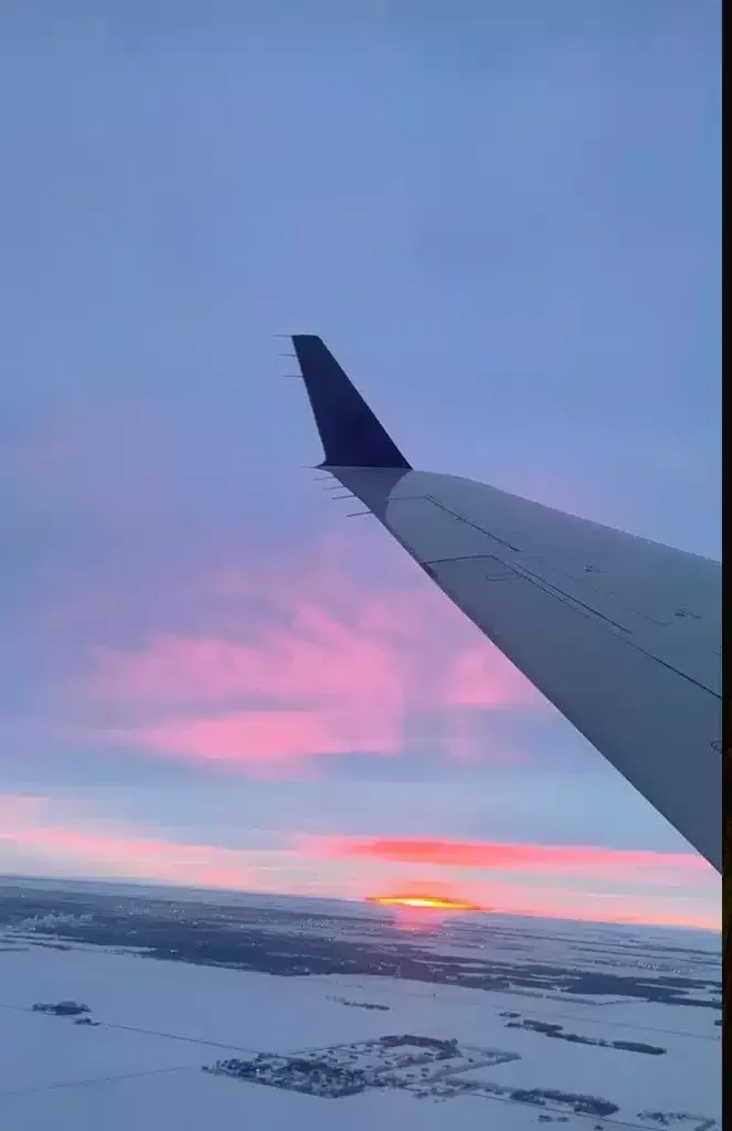 Sunset in North dakota, pink sky snowy white fields and airplane wing