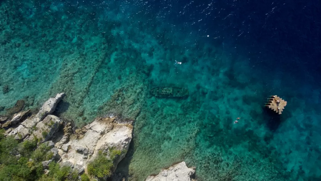 Shipwreck at Tugboat Beach drone shot of snorkeler with shipwreck in water