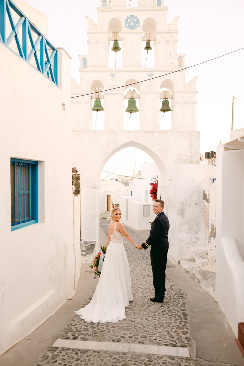 the author. and her husband in megalochori santorini under a six bell arch