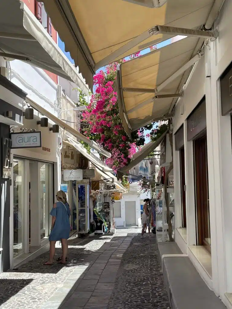 Bustling streets of Thira with small shops and pink flowers