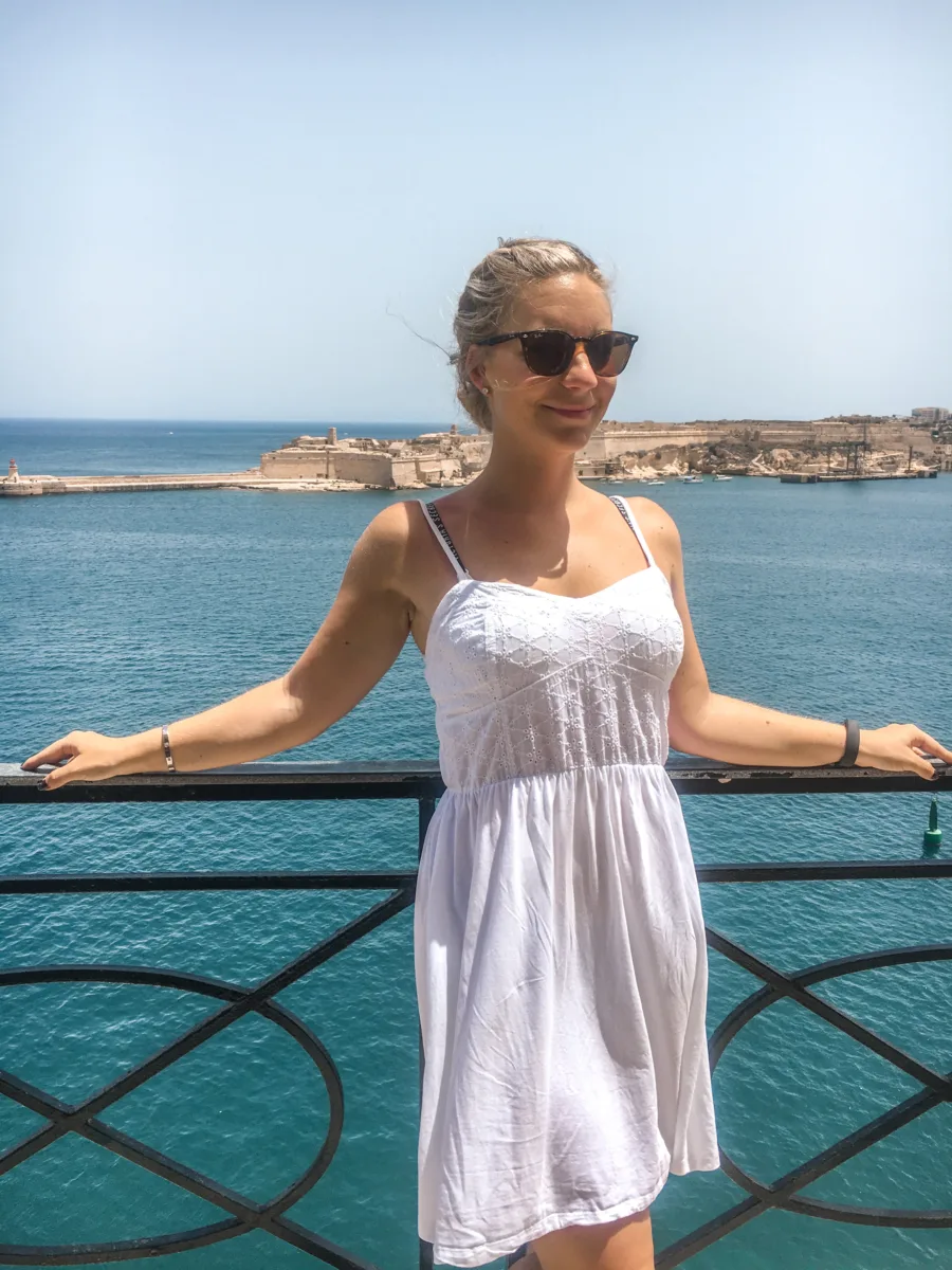 The author in a white dress standing on a viewpoint in Valletta malta 