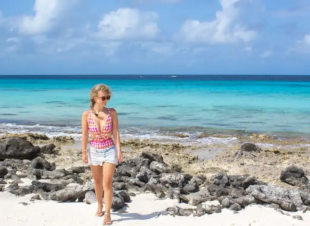 De auteur in een roze bikini voor de oceaan in Bonaire