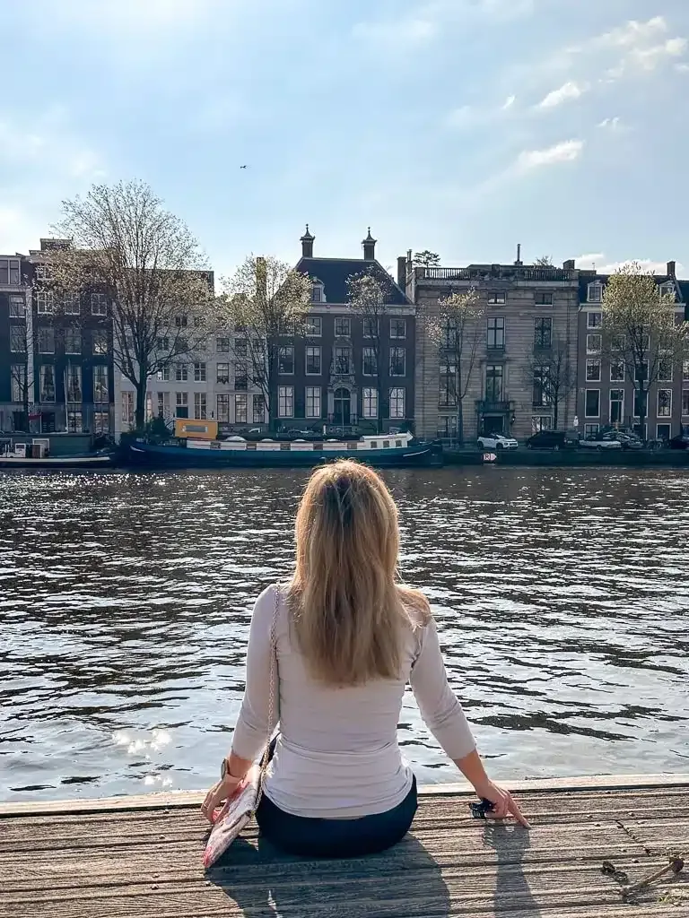 the author sitting in front of canal in amsterdam 