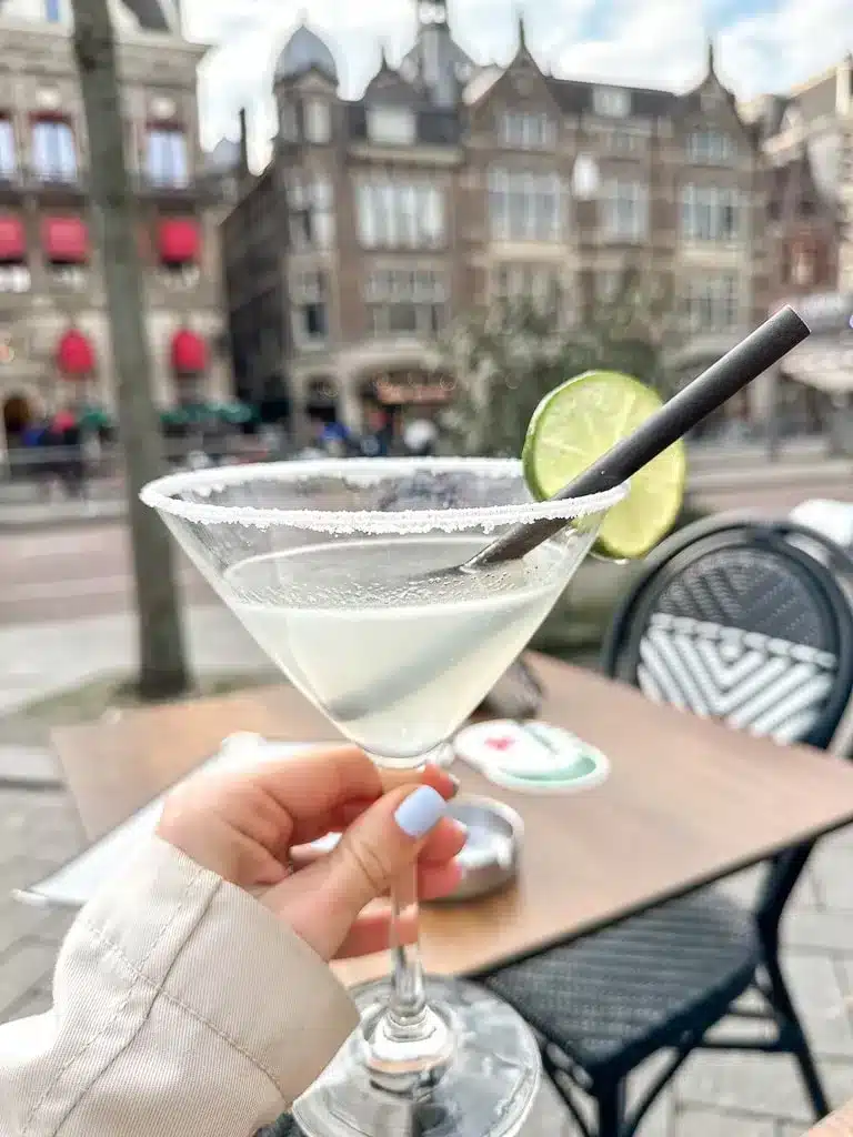 the author holing a cocktail in amsterdam on the damrak