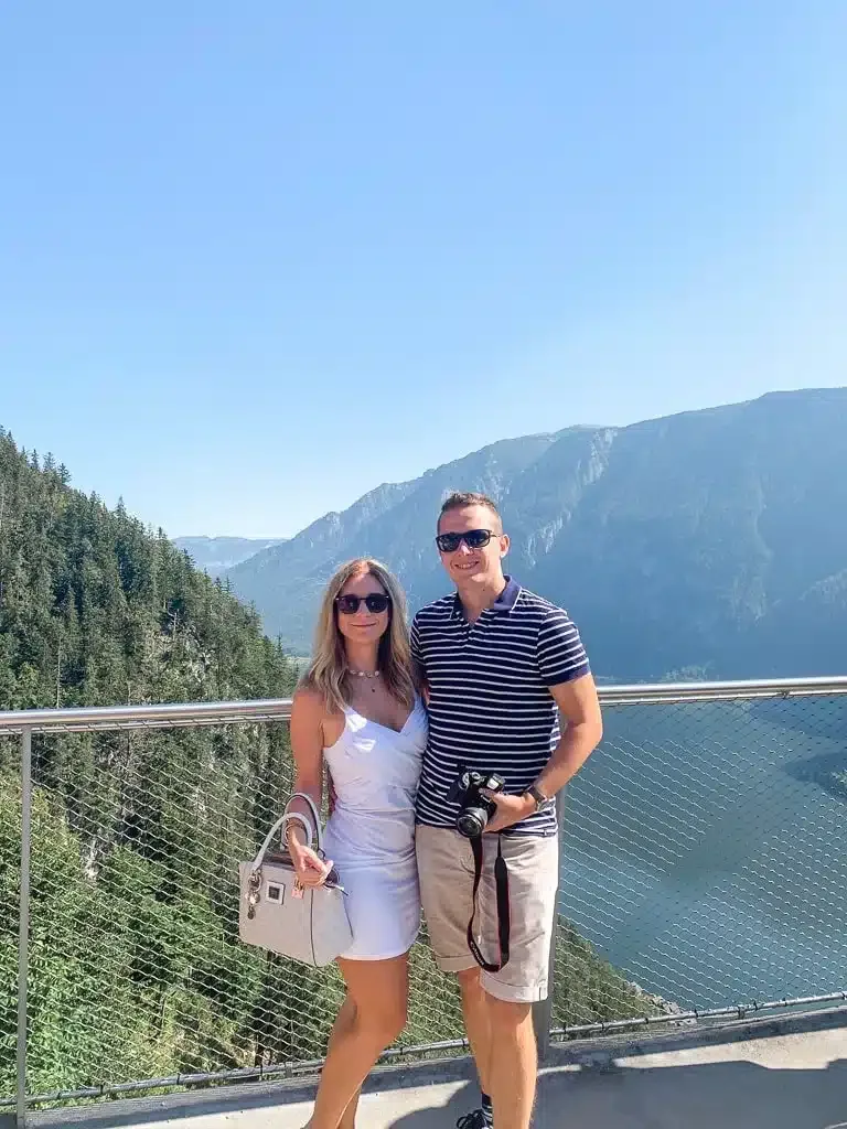 the author and her husband standing on top of the viewpoint in hallstatt overlooking the lake
