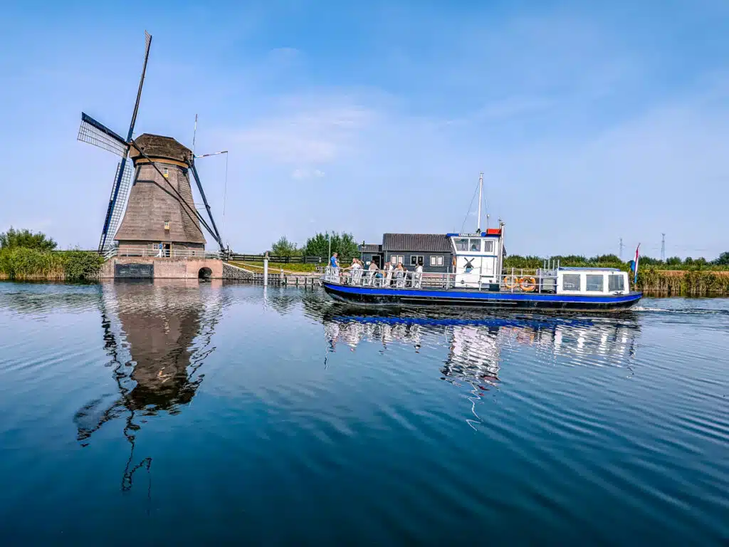 windmill in front of river at Kinderdijkje with boat on it 