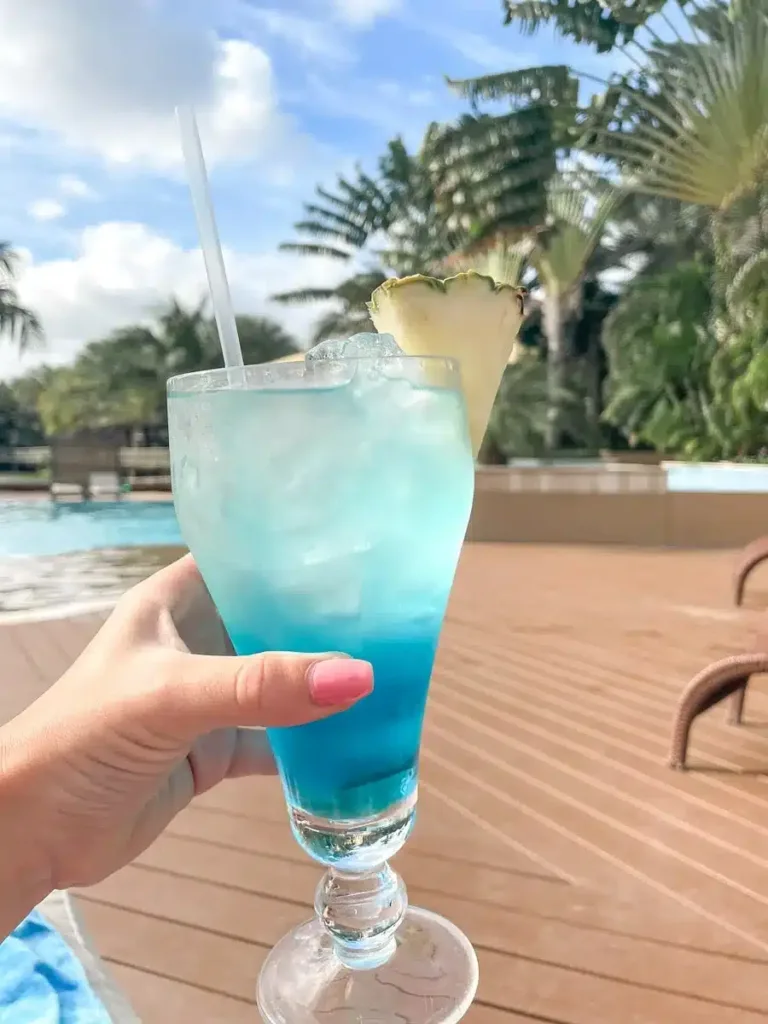 blue cocktail on a pool with palm trees in the background at acoya curacao