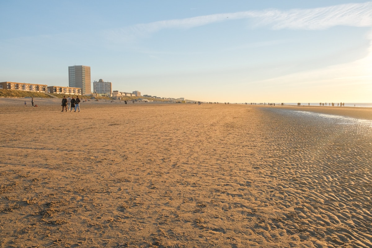 A big white sandy beach at sunset with a golden glow in Zandvoort weekend trip from Amsterdam 