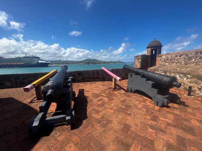 beautiful fortress with canons overlooking caribbean cruise port in the dominican republic with a big cruise ship in port 