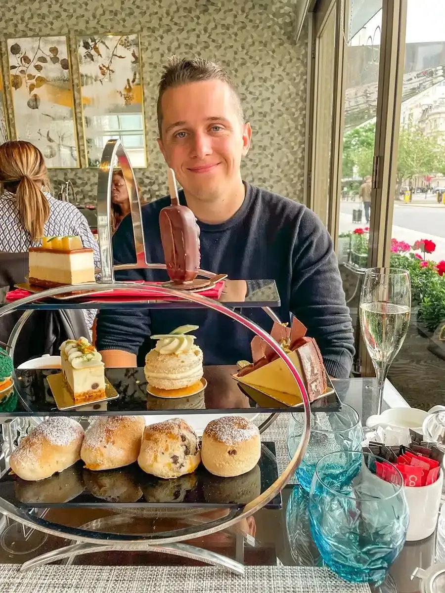 the husband of the author with a big high tea arrangement with scones and clotted cream in london