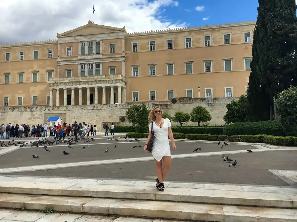 the author in athens in front of important building in a white dress 