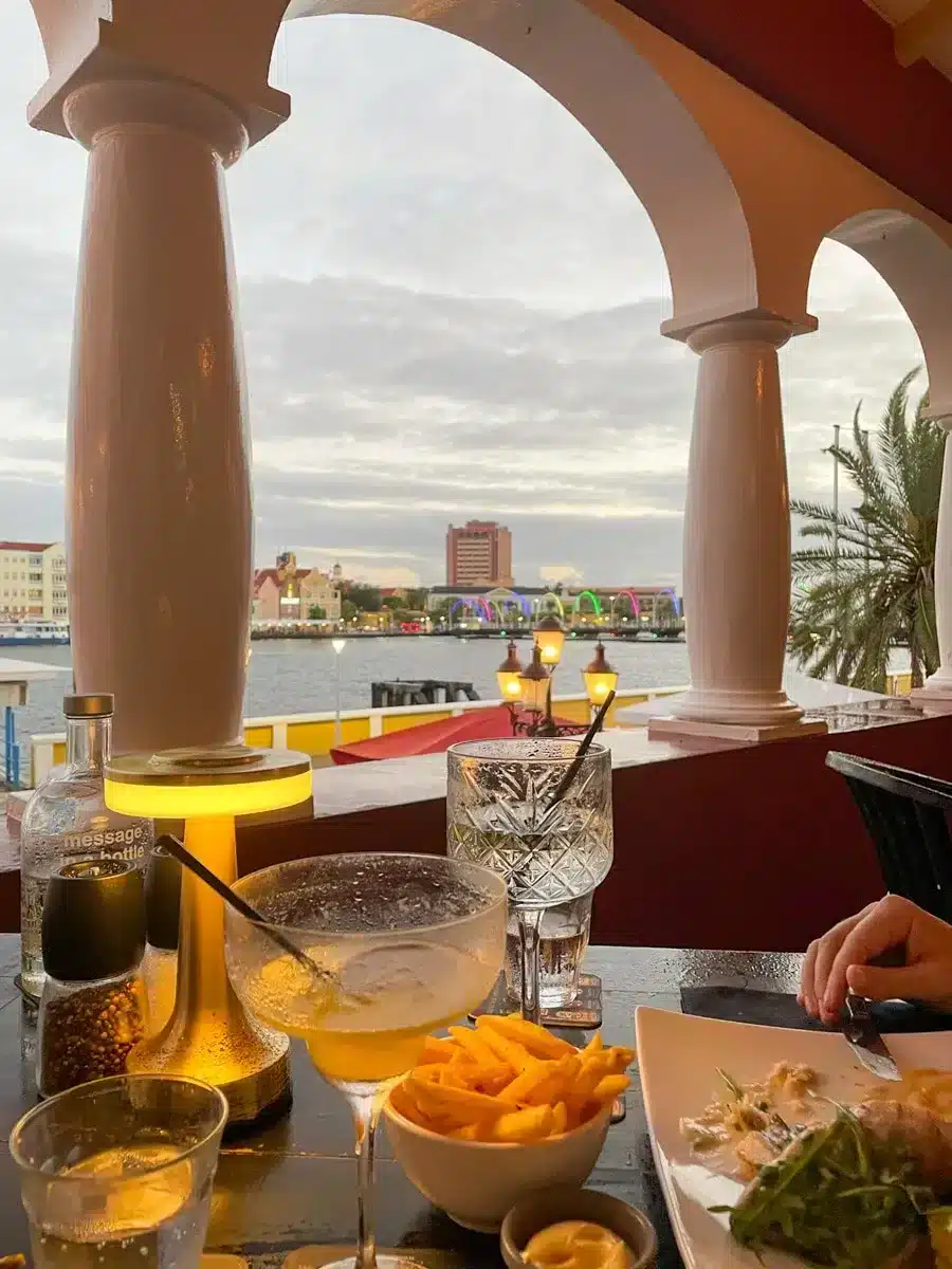 dinner with a view: a table set with lots of food and cocktails and in the background a view over the handelskade in curacao