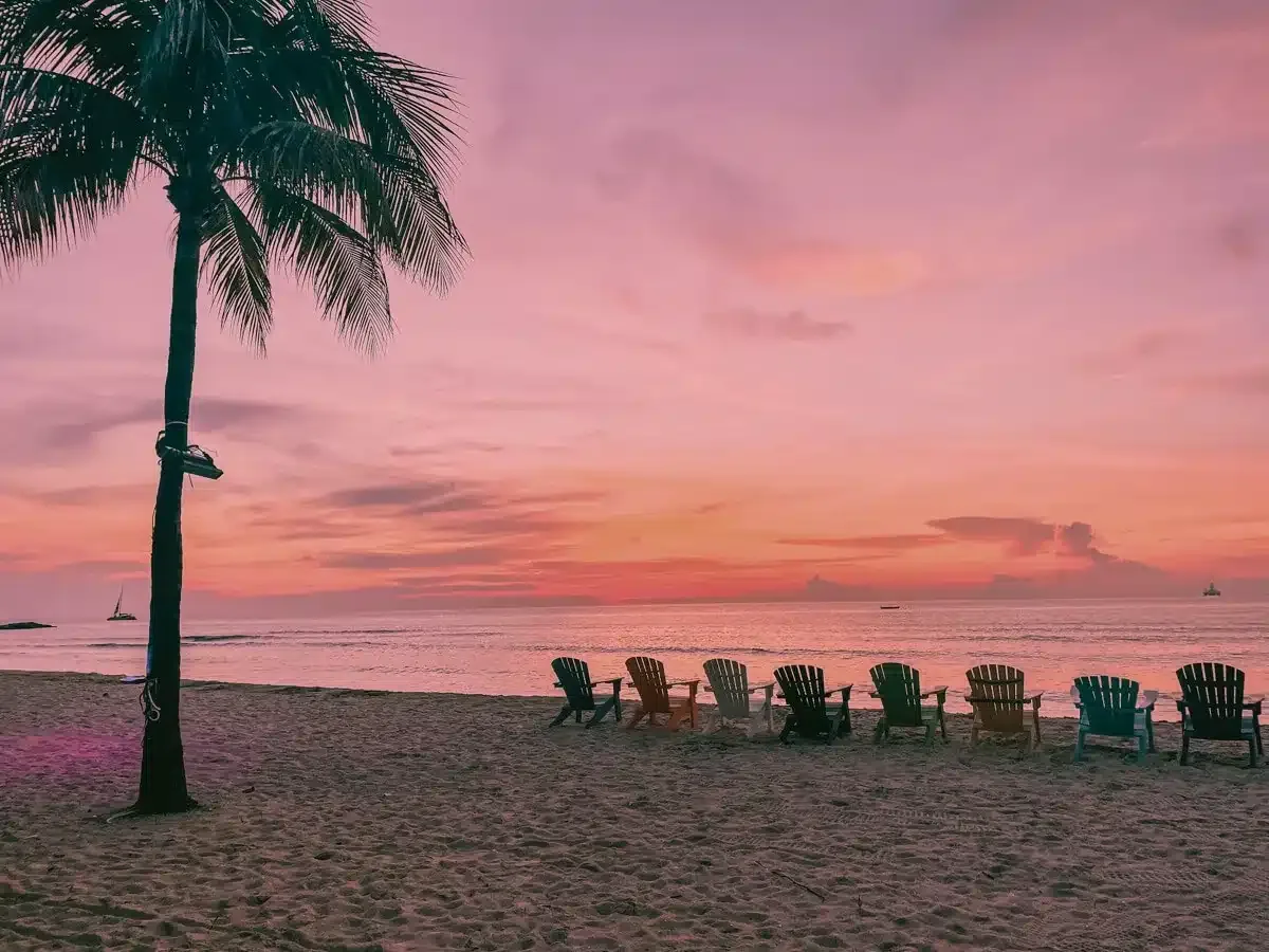 Aruba sunset with beautiful pink colors and beach chairs in a row
