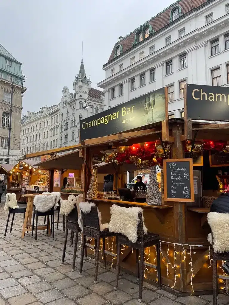 Christmas market in Vienna in winter with cozy chairs in front of a champagne bar 
