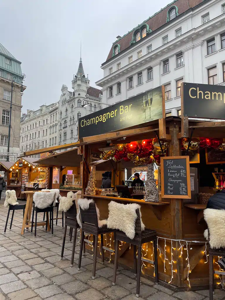 Christmas market in Vienna in winter with cozy chairs in front of a champagne bar 
