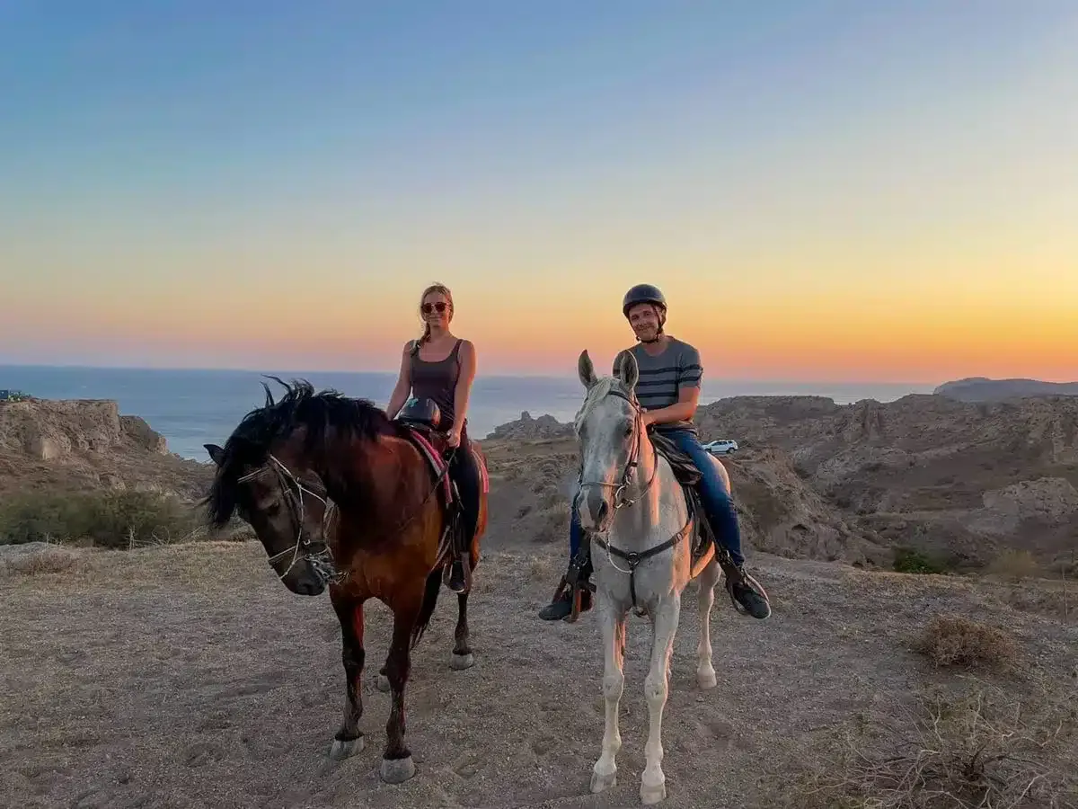 the author and her husband on two horses in santorini for sunset