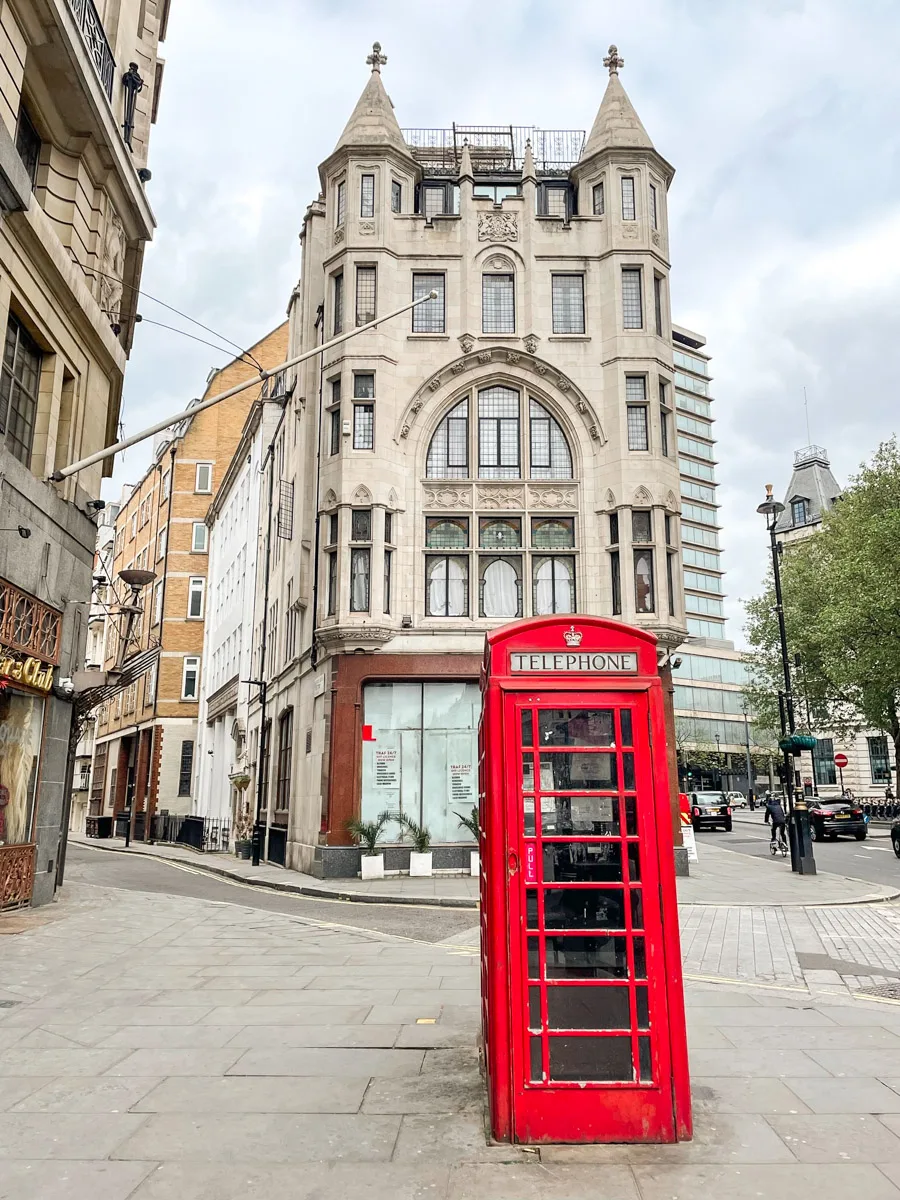typical london phone booth in red with a fancy building in the background