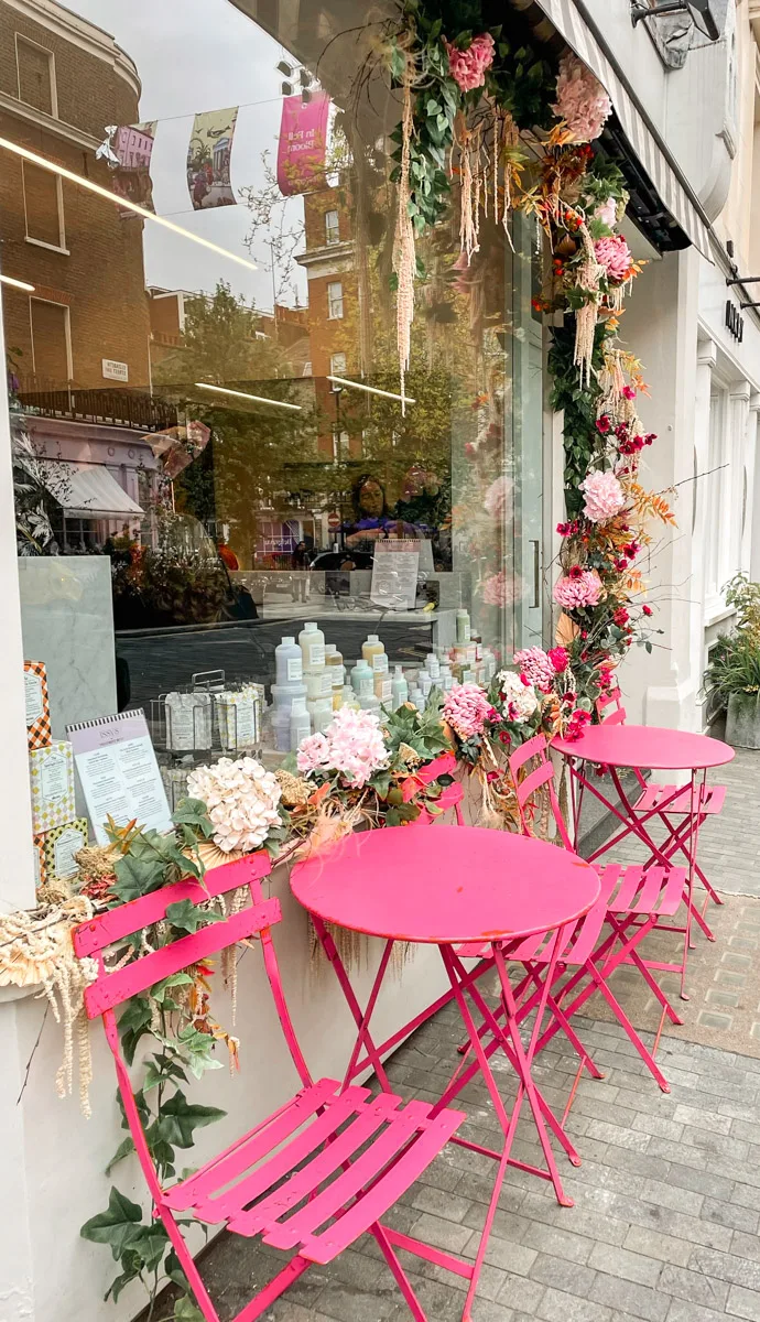 cute pink table and chairs in front of decorated storefront
