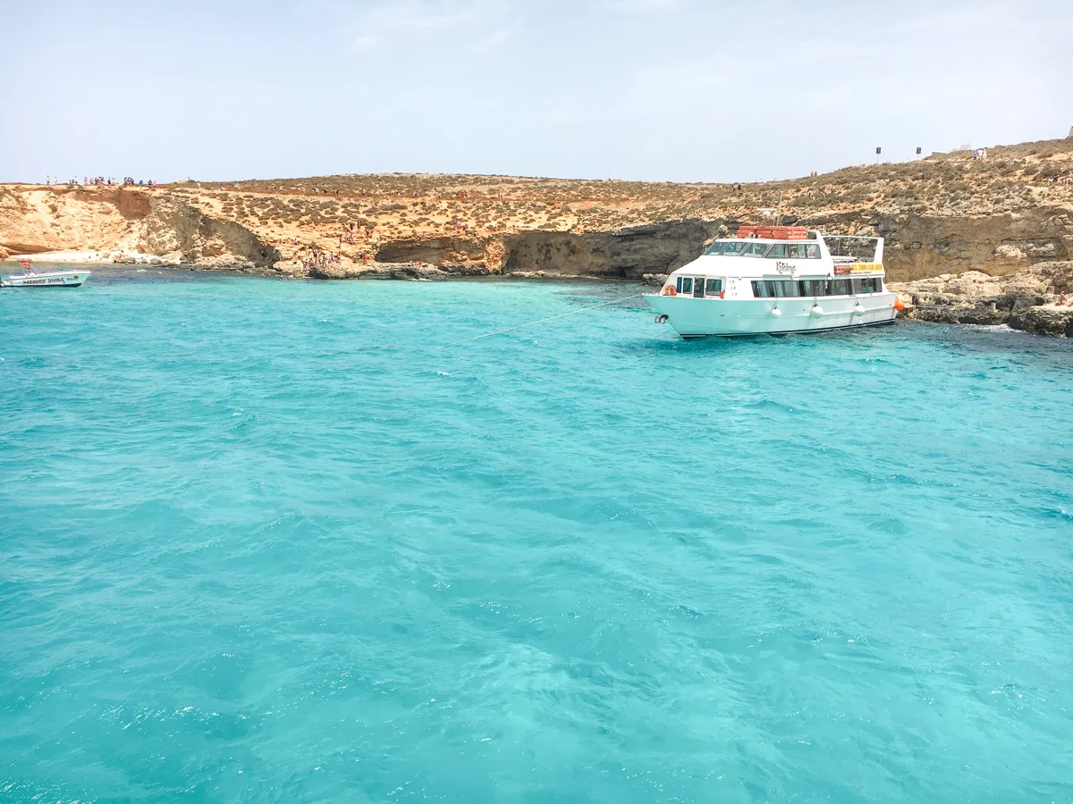 picture of a boat tendering in the blue lagoon in comino with stunning crystal clear blue water