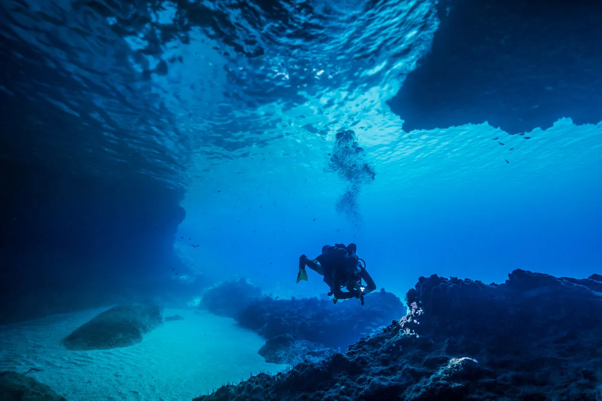 a scuba diver underwater in curacao with a flashlight