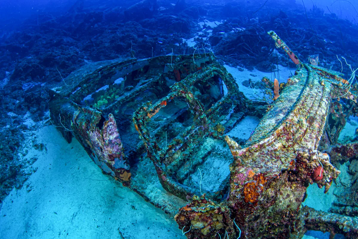 picture of a sunken wreck of a car underwater covered in corals on a car pile dive site near the sunscape hotel in curacao 