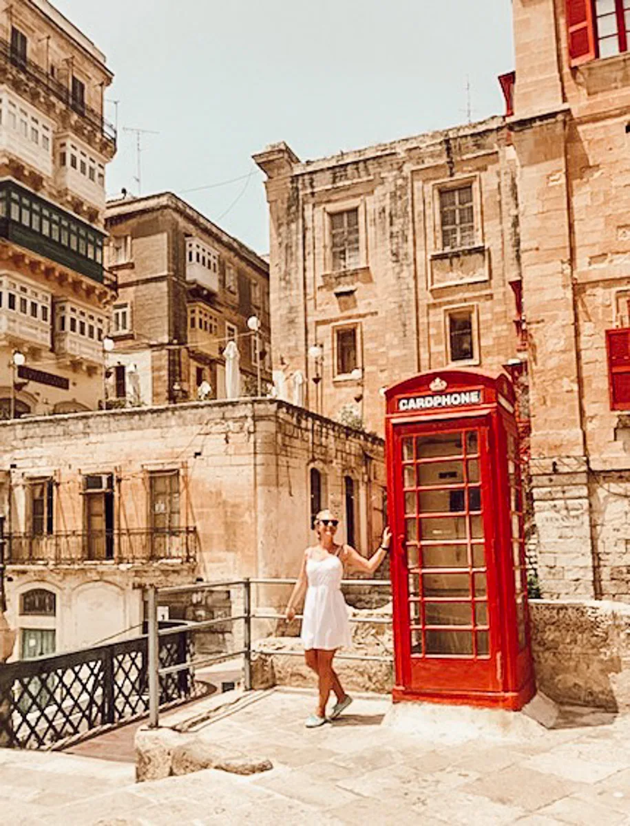 the author posing with a red phone booth in valletta