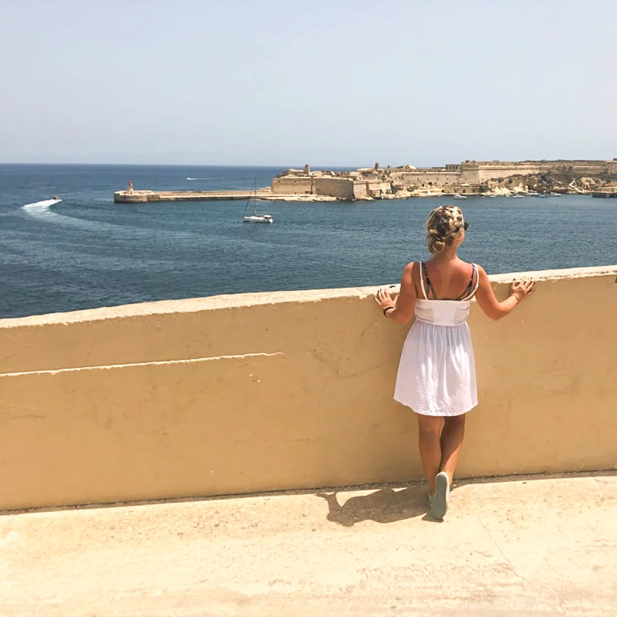 the author in malta standing on a platform overlooking the ocean