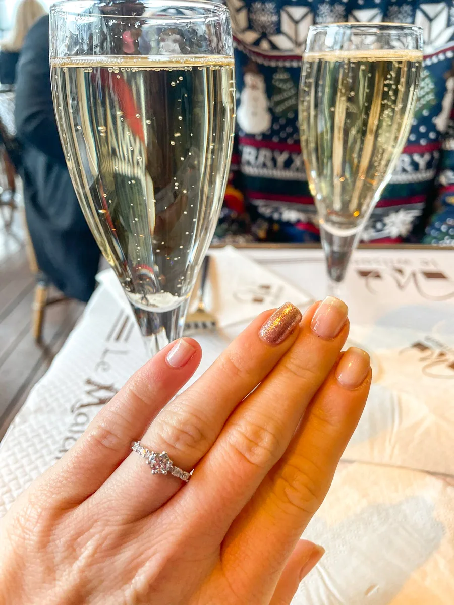two glasses of chamagne in paris with the authors hand showing an engagement ring