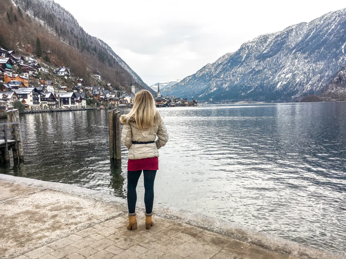the author standing on a lake near a mountain enjoying the view of a scenic little village in austria